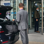 Driver in an elegant suit looking at his passenger standing at the airport terminal entrance at san diego international airport on the way to LAX